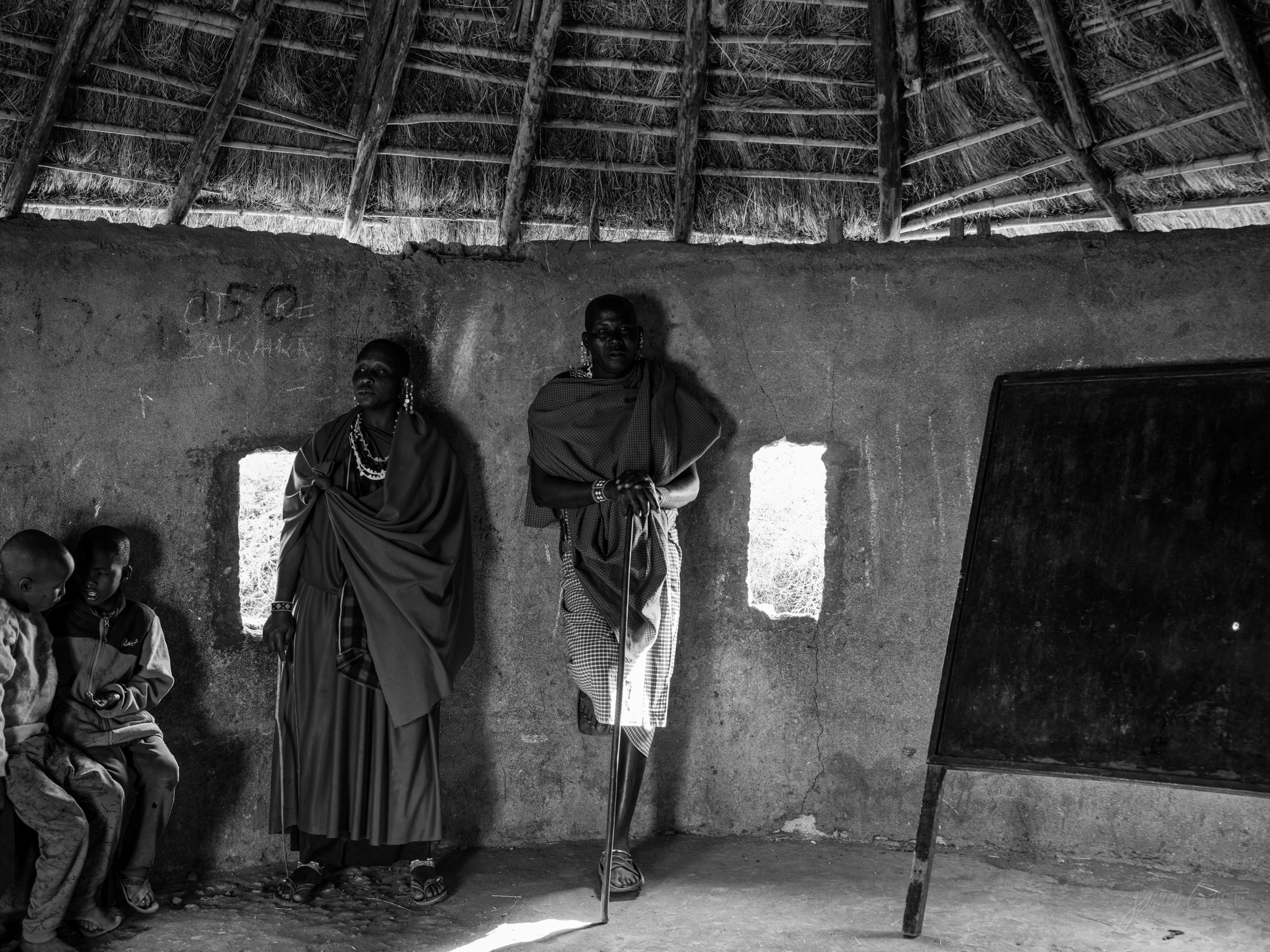 Black and white view of the same interior, figures in the low dark room lit by a single small window.